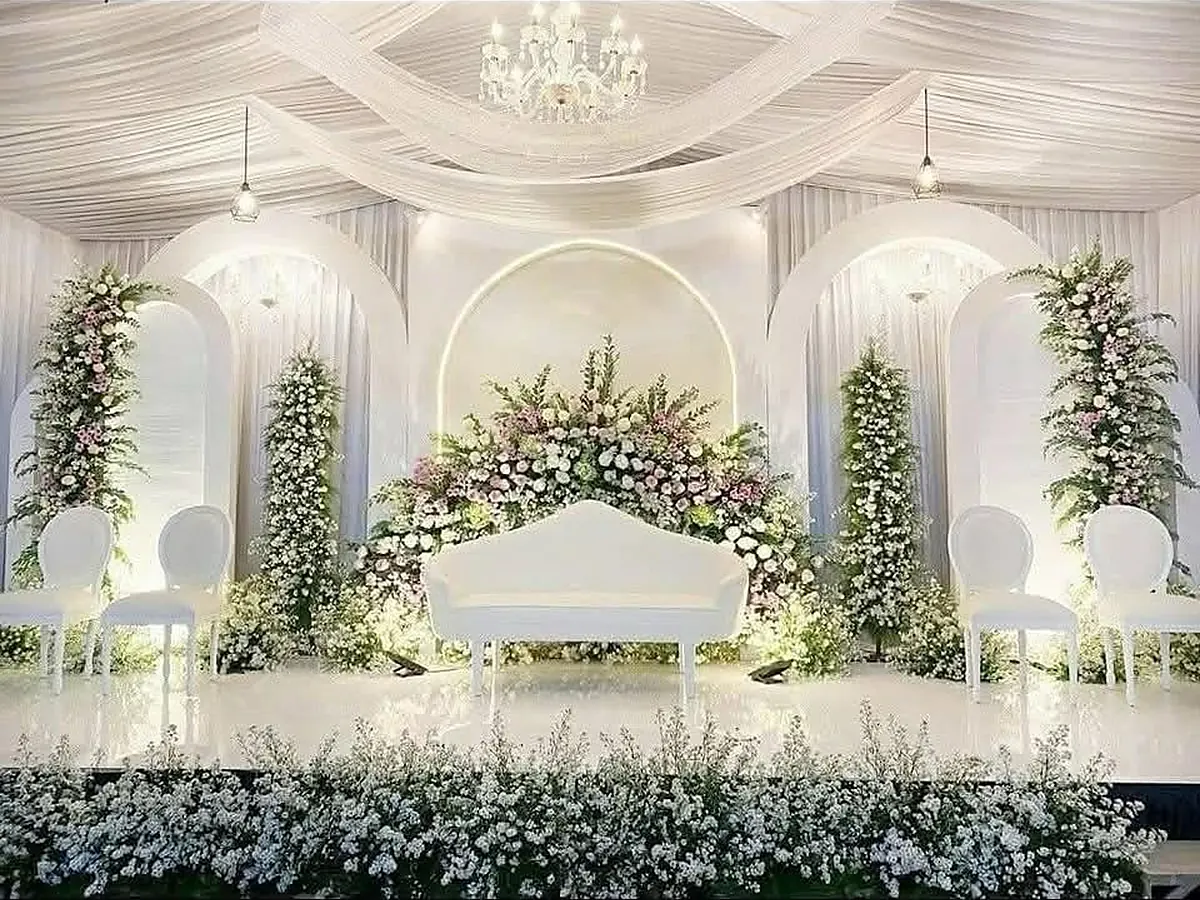 White floral wedding stage with draped ceiling and chandelier